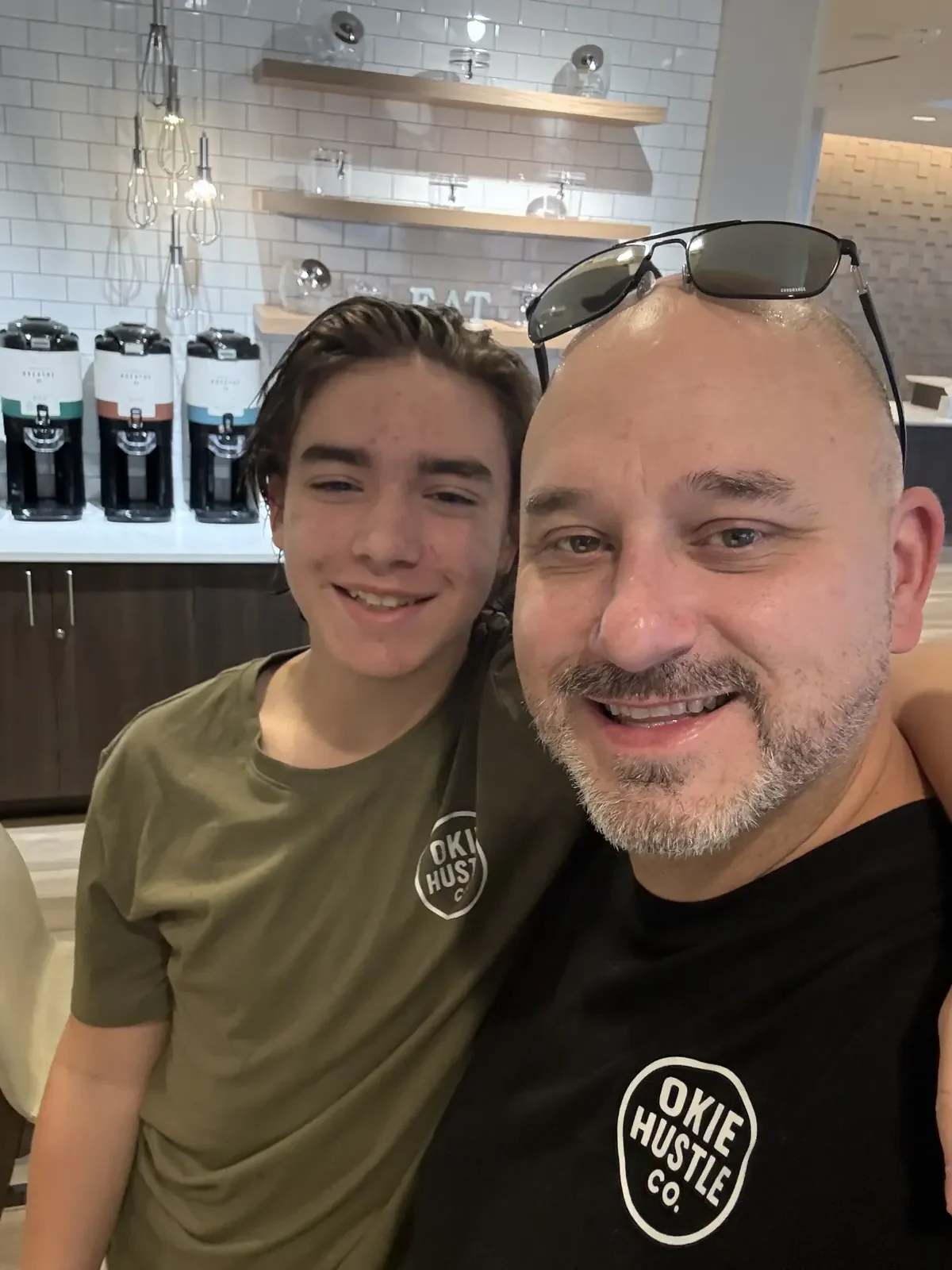 Bill with his son, both wearing Okie Hustle Co. shirts